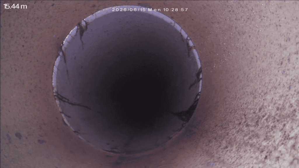 Close-up of a large underground pipe with visible cracks and wear.